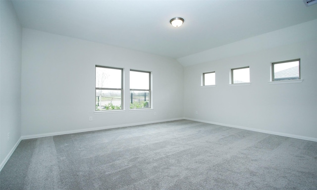 carpeted empty room featuring vaulted ceiling