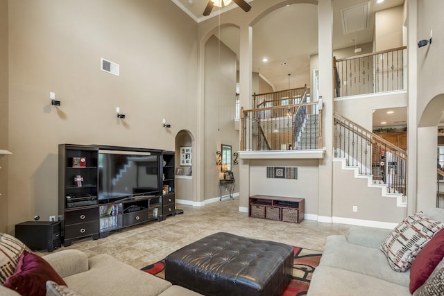 living room featuring ceiling fan, a towering ceiling, and crown molding