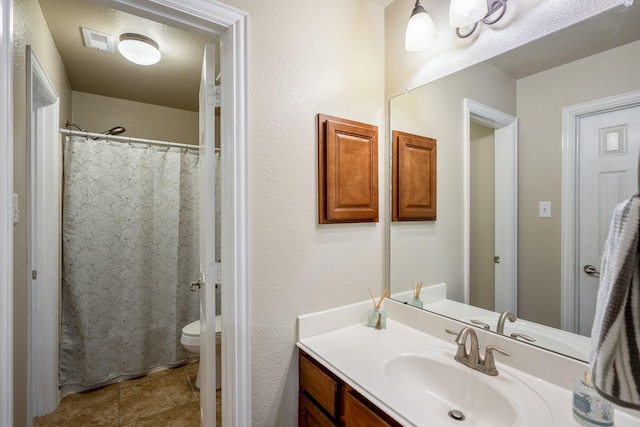 bathroom with vanity, curtained shower, a textured ceiling, and toilet