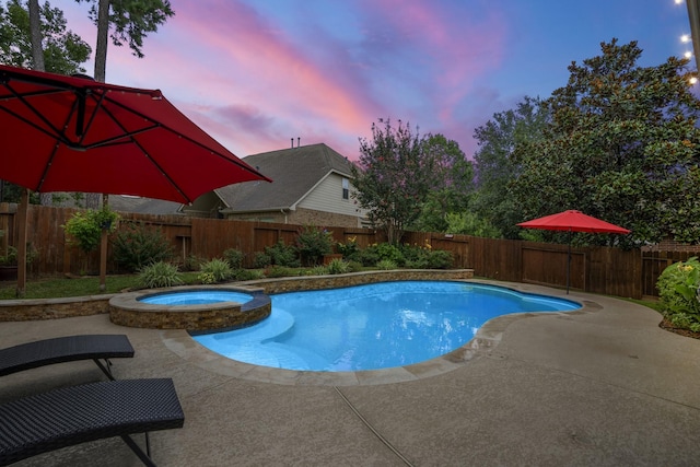 pool at dusk with an in ground hot tub and a patio area