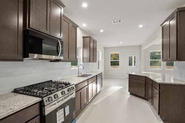 kitchen featuring light stone countertops, appliances with stainless steel finishes, tasteful backsplash, and sink