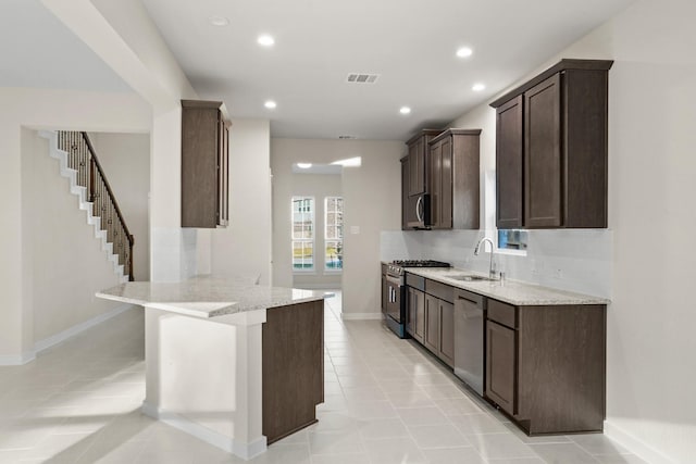 kitchen with sink, light stone counters, light tile patterned floors, and stainless steel appliances