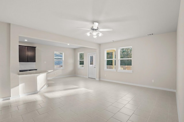 unfurnished living room with ceiling fan, a healthy amount of sunlight, and light tile patterned flooring