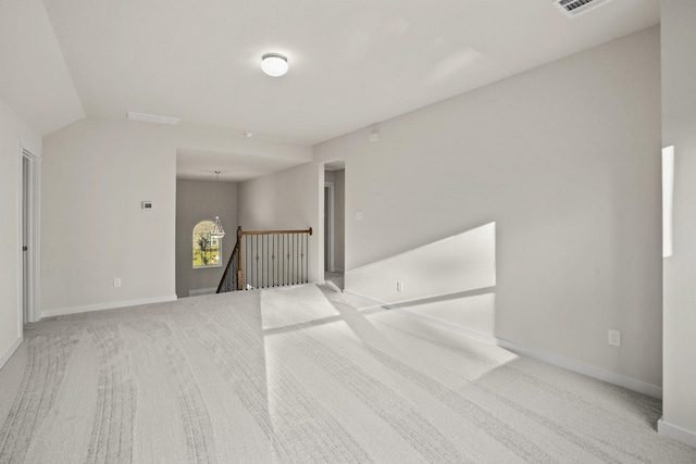 carpeted empty room with vaulted ceiling