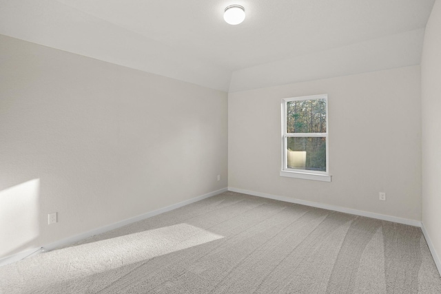 empty room featuring carpet floors and vaulted ceiling