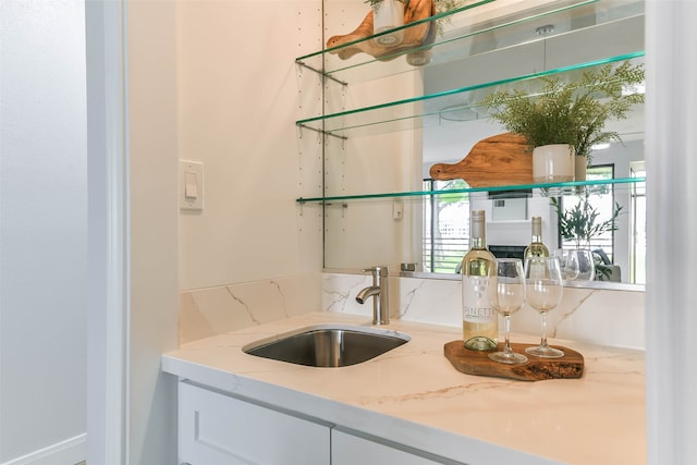 bar featuring white cabinetry, light stone countertops, tasteful backsplash, and sink