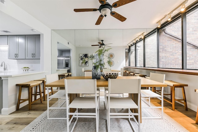 dining room with sink, light hardwood / wood-style flooring, and ceiling fan