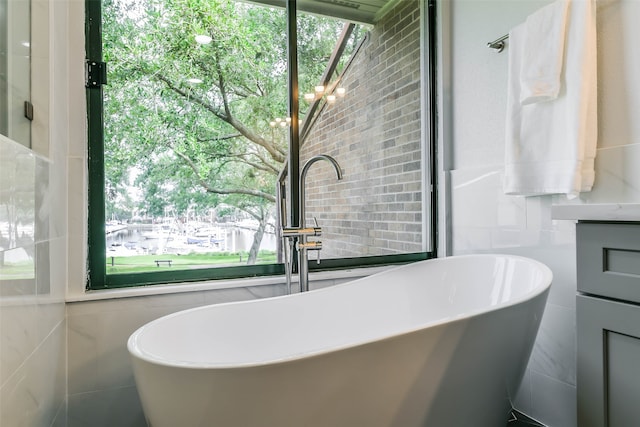 bathroom with tile walls, a wealth of natural light, and a tub