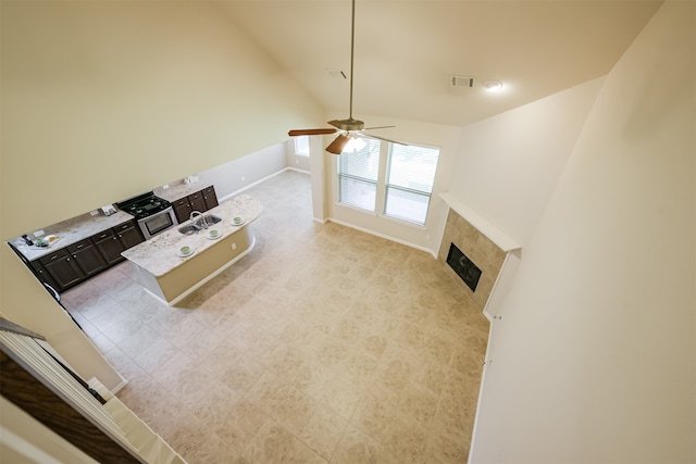 unfurnished living room featuring vaulted ceiling, ceiling fan, and a fireplace