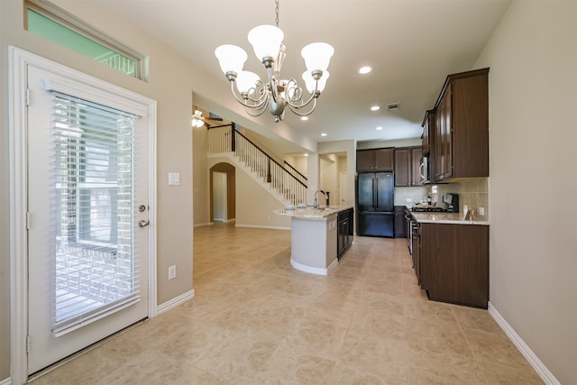 kitchen with dark brown cabinetry, sink, hanging light fixtures, stainless steel appliances, and a kitchen island with sink