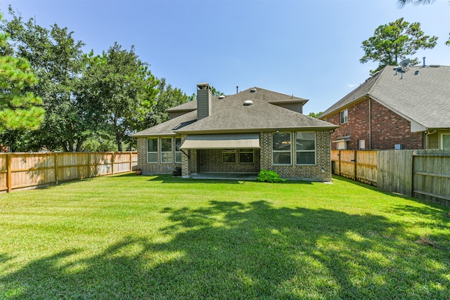 rear view of house featuring a yard and a patio