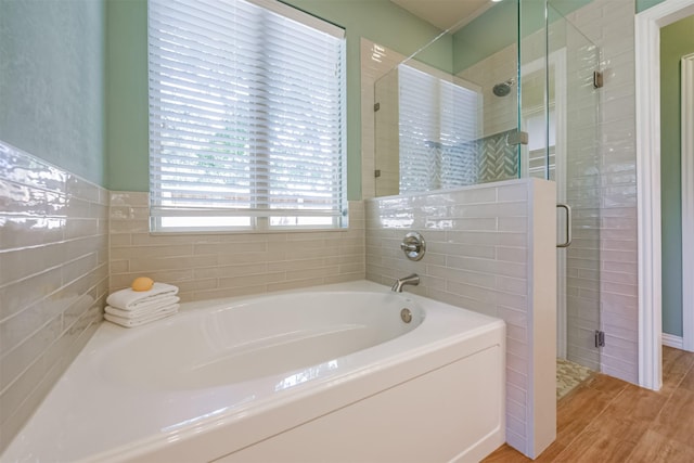 bathroom with hardwood / wood-style flooring, shower with separate bathtub, and tile walls