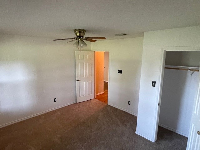 unfurnished bedroom featuring dark carpet, ceiling fan, and a closet