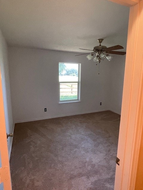 empty room featuring ceiling fan and dark carpet