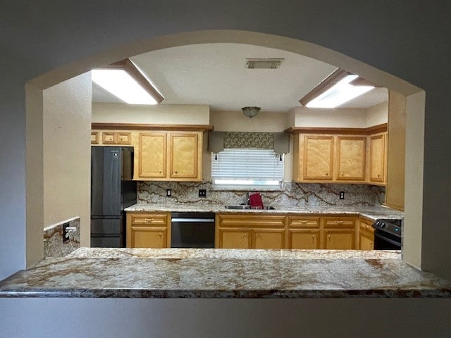 kitchen with decorative backsplash, black appliances, light stone countertops, and sink