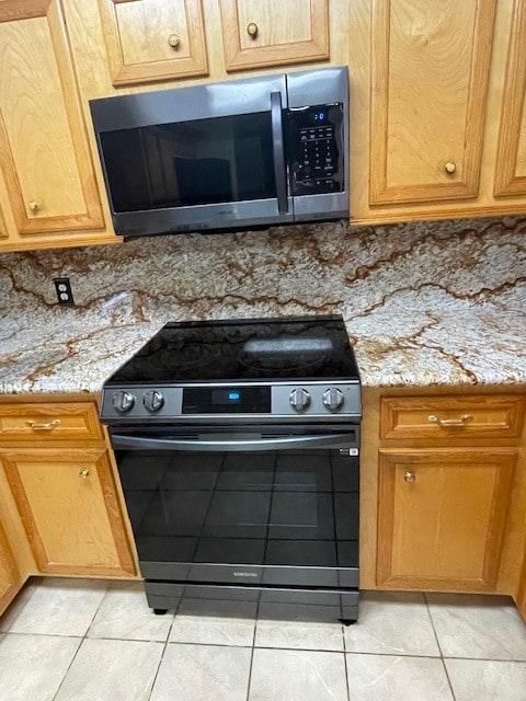 kitchen featuring light stone countertops, black range with gas cooktop, and light tile patterned floors