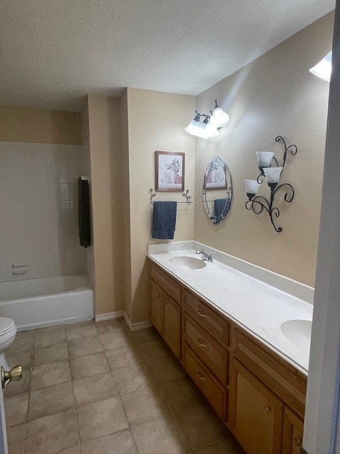 full bathroom with tile patterned flooring, a textured ceiling, double vanity, tiled shower / bath combo, and toilet