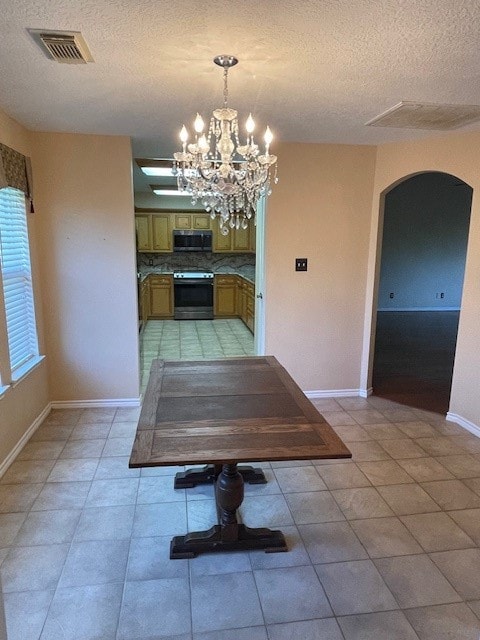 unfurnished dining area featuring an inviting chandelier, a textured ceiling, and light tile patterned floors