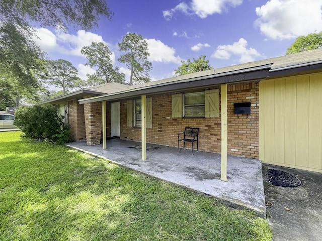 exterior space featuring a patio area, a lawn, and brick siding