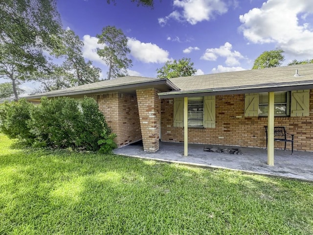 rear view of house featuring brick siding and a yard