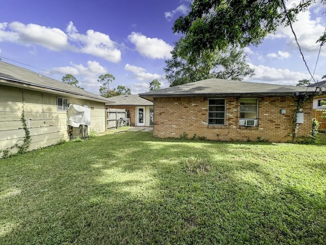 back of property with cooling unit, brick siding, a yard, and fence