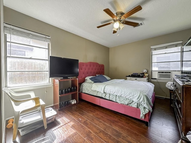 bedroom with a textured ceiling, multiple windows, wood-type flooring, and cooling unit