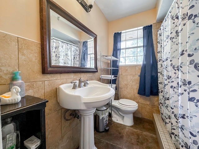 bathroom featuring toilet, tile patterned floors, and tile walls