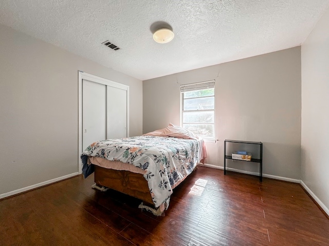 bedroom featuring wood-type flooring, a closet, and a textured ceiling