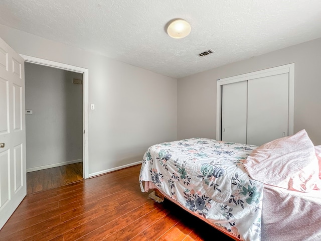 bedroom featuring a textured ceiling, a closet, and wood-type flooring