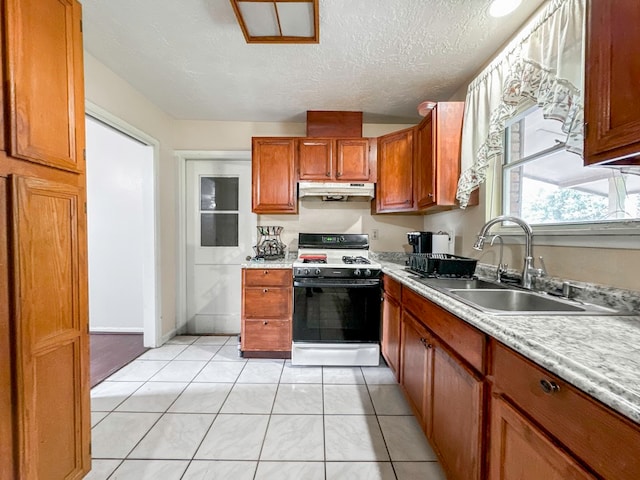 kitchen featuring light tile patterned floors, white gas range oven, sink, and a textured ceiling