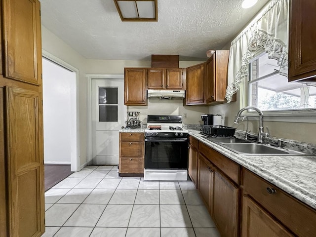 kitchen featuring brown cabinetry, gas range oven, light countertops, and a sink