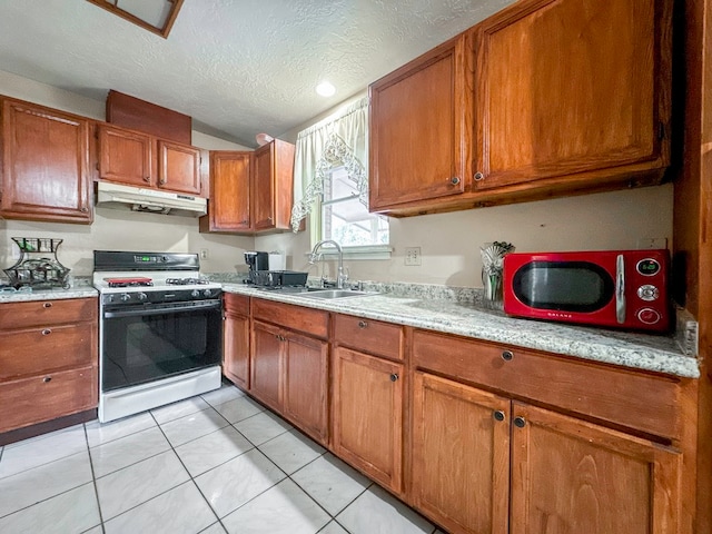 kitchen with light tile patterned flooring, a textured ceiling, light stone countertops, white range with gas stovetop, and sink