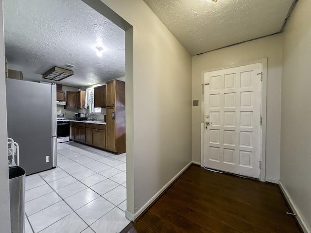 foyer featuring visible vents, a textured ceiling, baseboards, and light wood finished floors