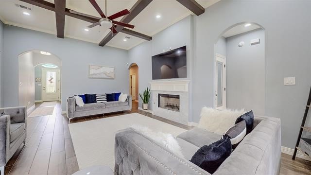 living room with beamed ceiling, hardwood / wood-style flooring, coffered ceiling, ceiling fan, and a towering ceiling