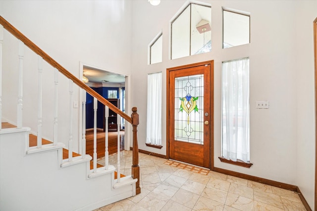 entrance foyer featuring a high ceiling, marble finish floor, stairs, and baseboards