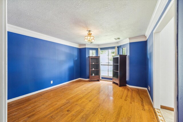 unfurnished room featuring a notable chandelier, a textured ceiling, hardwood / wood-style flooring, and crown molding