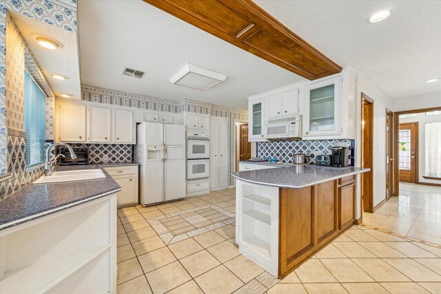 kitchen with white cabinets, white appliances, sink, light tile patterned floors, and decorative backsplash