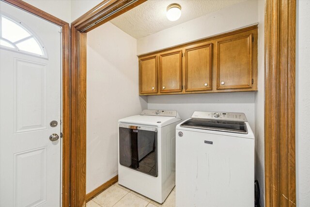 laundry area featuring cabinets, washing machine and dryer, a textured ceiling, and light tile patterned floors