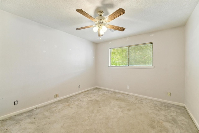 spare room with light carpet, a ceiling fan, baseboards, and a textured ceiling