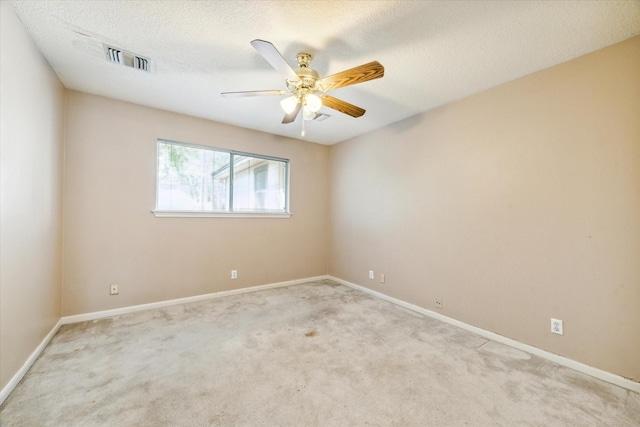 spare room featuring ceiling fan, visible vents, a textured ceiling, and light colored carpet