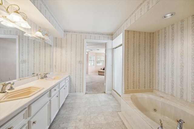 full bathroom with double vanity, wallpapered walls, baseboards, a tub with jets, and a sink