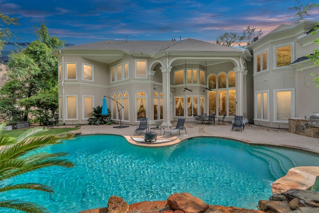 pool at dusk featuring a patio area and ceiling fan