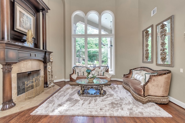 living room with wood-type flooring, a tiled fireplace, and high vaulted ceiling