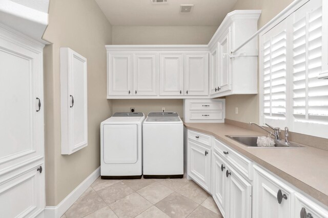 laundry room with washing machine and clothes dryer, a healthy amount of sunlight, sink, and light tile patterned floors