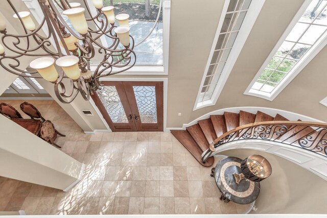 entrance foyer featuring a high ceiling, a chandelier, tile patterned flooring, and french doors