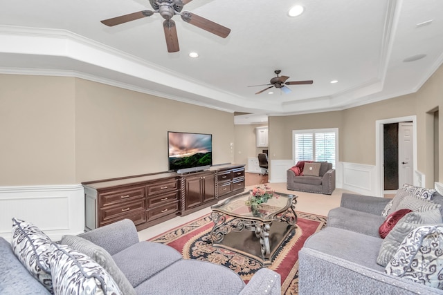 living room featuring ornamental molding, ceiling fan, and a raised ceiling