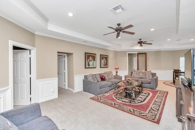 carpeted living room featuring ceiling fan, ornamental molding, and a tray ceiling