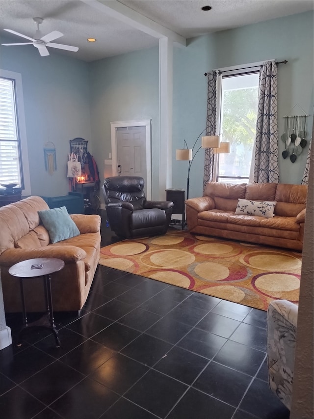 living room featuring dark tile patterned flooring, ceiling fan, and a textured ceiling