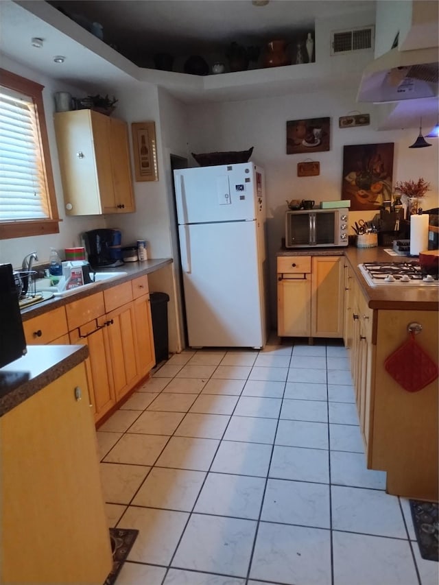 kitchen featuring gas cooktop, stainless steel microwave, visible vents, freestanding refrigerator, and extractor fan