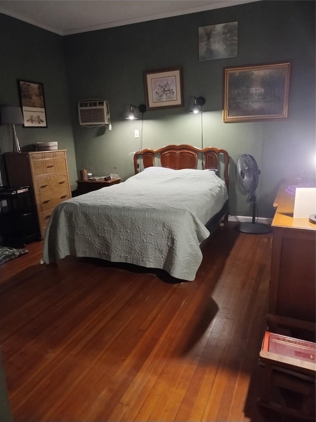 bedroom with wood finished floors, a wall unit AC, and ornamental molding